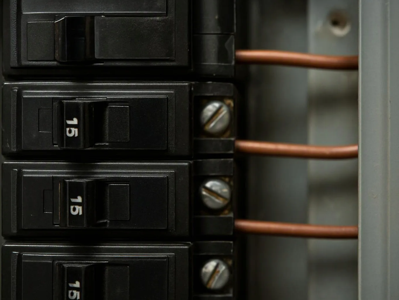 Close-up of black circuit breakers with copper wires inside an electrical panel