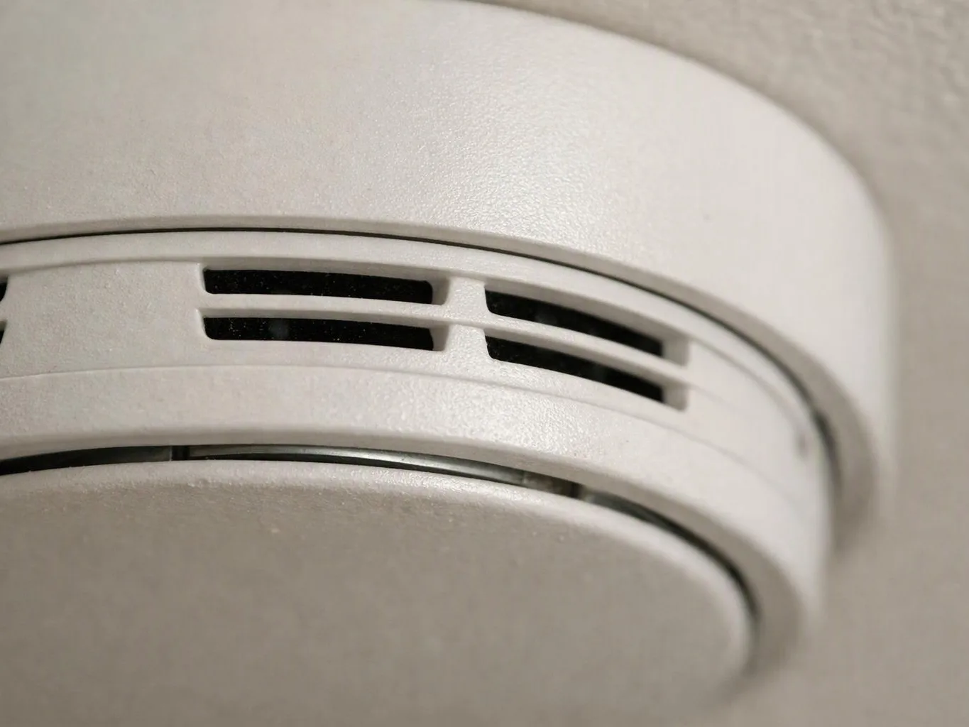 Close-up of a white smoke detector mounted on a ceiling or wall